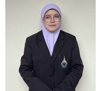 ภาพหญิงนักศึกษาสวมชุดทางการและผ้าคลุมหัว สีม่วงอ่อน ยืนอยู่หน้าผนังสีอ่อน แสดงความเป็นมืออาชีพและความภาคภูมิใจในวัฒนธรรมอิสลามและภาษาอาหรับ.