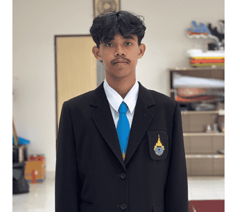 ภาพนักเรียนชายในชุดเครื่องแบบโรงเรียนอิสลามและอาหรับศึกษา มนร. ยืนอยู่ในห้องเรียนหรืออาคารเรียน พร้อมโลโก้โรงเรียนบนเสื้อผ้า.